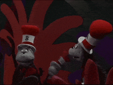 two stuffed animals wearing red hats are standing next to each other in a dark room .