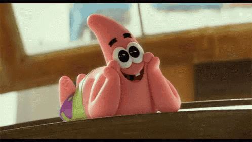 patrick star from spongebob squarepants is smiling and laying on a table .