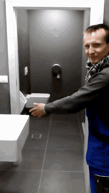 a man standing in a bathroom with a toilet and sink