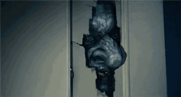 a monster is crawling out of a hole in the wall .
