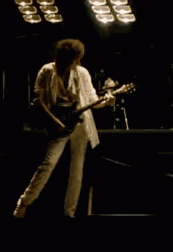 a man is playing a guitar on a stage in front of a row of lights