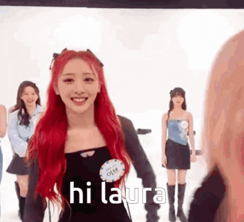 a girl with red hair is standing in front of a group of girls and says hi laura