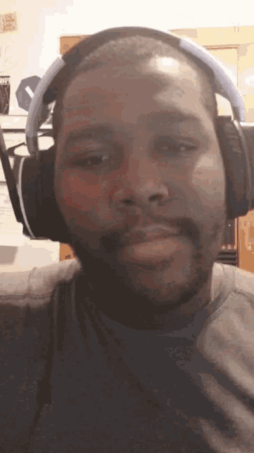 a man wearing headphones looks at the camera with a sticker on the wall that says ' i love you '