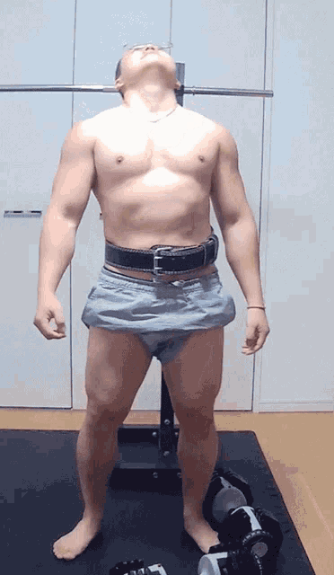 a man without a shirt is standing in a gym