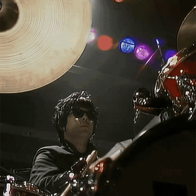 a man wearing sunglasses is playing drums in front of a drum set with a cymbal that says sabian
