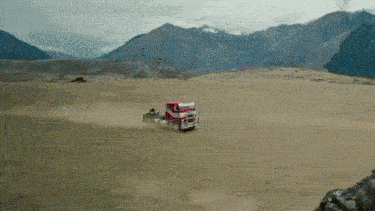 a red truck is driving on a dirt road in the desert