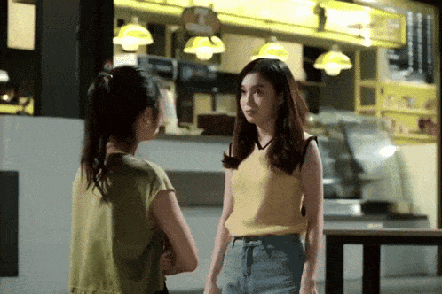 two women are standing in front of a restaurant with a sign that says t.