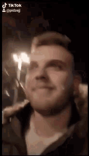 a man with a tear running down his face is smiling in a tiktok video