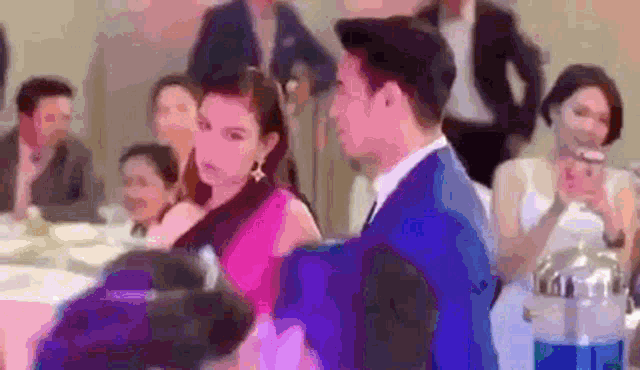 a man and a woman are sitting at a table in a crowded room .
