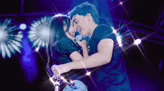 a man and a woman are hugging and singing into microphones