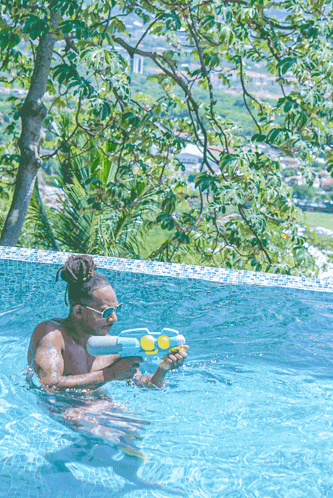 a man in a swimming pool holding a blue water gun