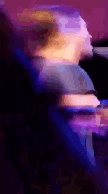 a blurry picture of a person in a dark room with purple and blue lights behind them