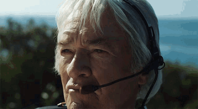 a man with gray hair is wearing a headset with a microphone attached to it