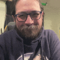 a man with a beard wearing glasses and a blue sweatshirt