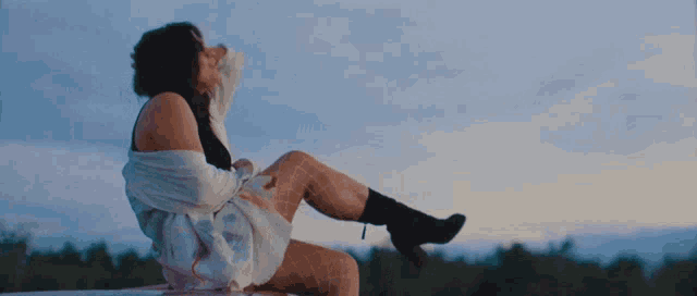 a woman is sitting on the roof of a car with her legs up