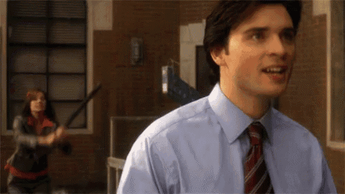 a man in a blue shirt and tie is smiling in front of a woman holding a bat .