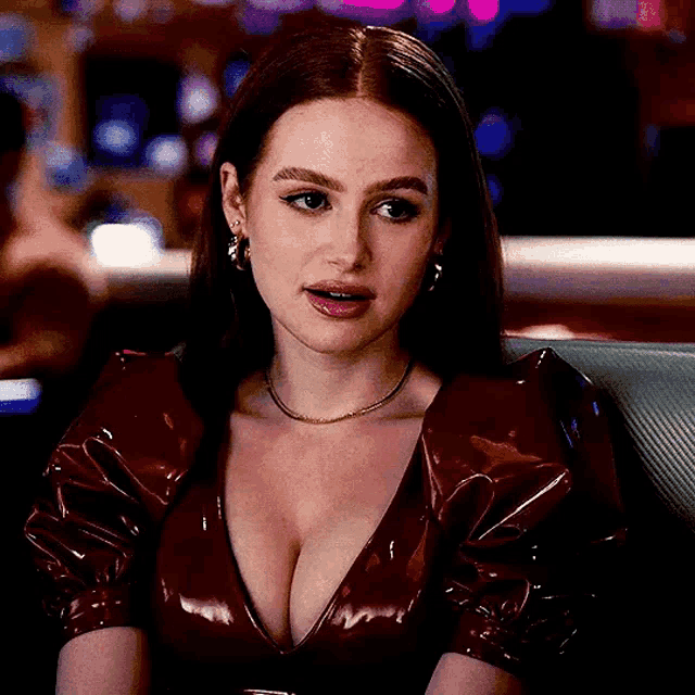 a woman in a red dress with a plunging neckline is sitting in a chair in a casino .