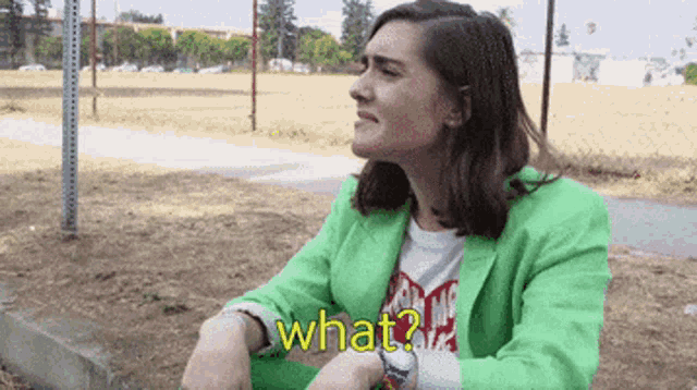a woman in a green jacket is sitting on the ground and says what ?