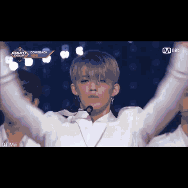 a man in a white shirt with a microphone stands on a stage in front of a sign that says comeback