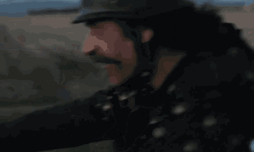 a man with a mustache is wearing a helmet while riding a bike .
