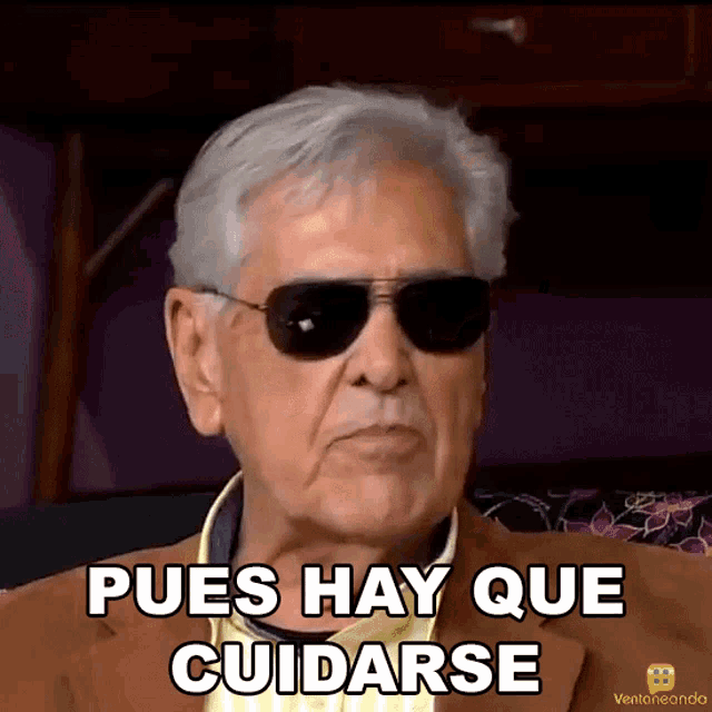 a man wearing sunglasses and a suit says pues hay que cuidarse