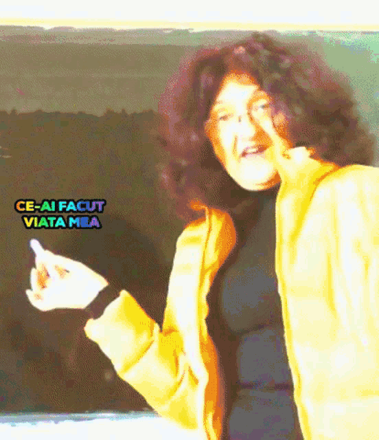 a woman in a yellow jacket is giving the middle finger in front of a blackboard