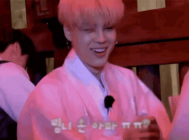 a young man in a pink kimono is smiling while standing next to a group of people .