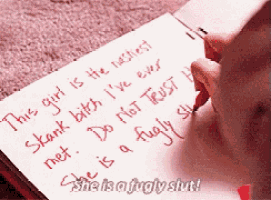 a person is writing on a piece of paper that says this girl is the nastiest shank bitch i 've ever met