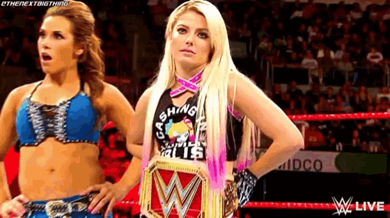 two women are standing in a wrestling ring with their hands on their hips