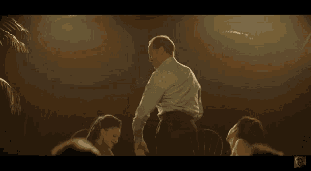 a man in a white shirt is dancing in front of two women