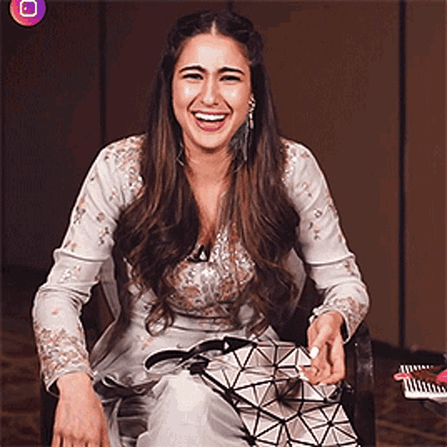 a woman in a white dress is sitting in a chair and smiling