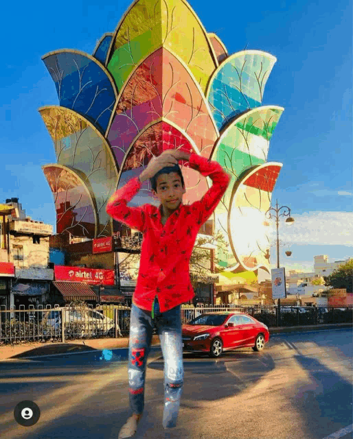 a boy in a red shirt is standing in front of a colorful building that says airtel 4g
