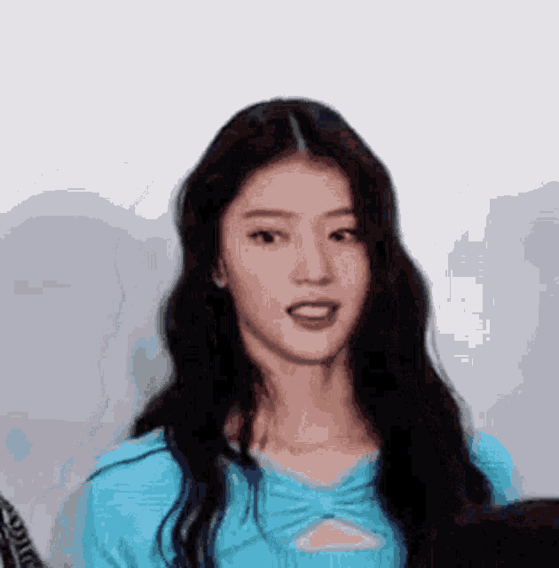 a close up of a woman with long hair wearing a blue shirt .