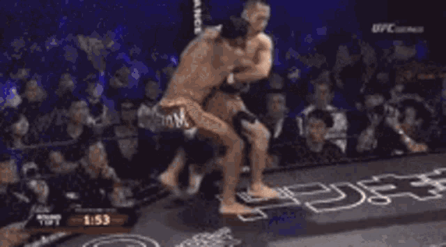 two men are wrestling in a ring and one of them is wearing a black shirt that says pancrase .
