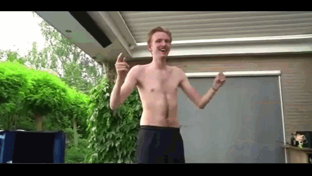 a man without a shirt is dancing in front of a building