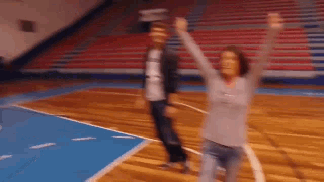 a man and a woman are dancing on a basketball court in a gym .