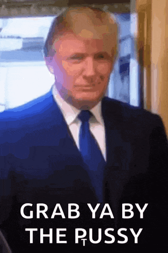 a man in a suit and tie is standing in front of a sign that says grab ya by the pussy .