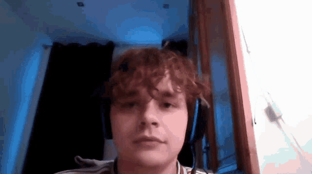 a young man with curly hair is wearing headphones