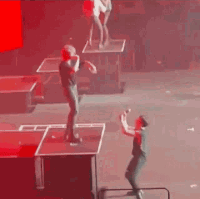 a man is standing on a stage holding a microphone while another man stands on a table .