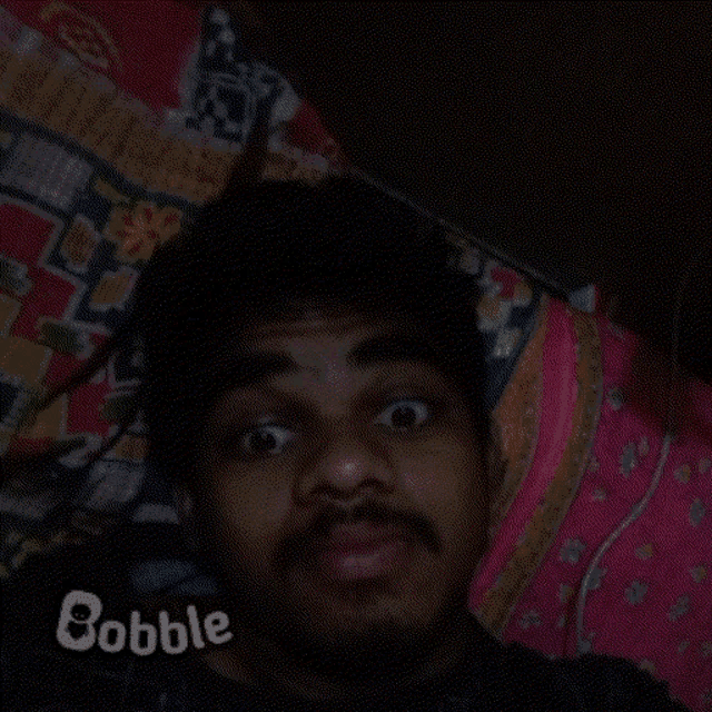 a man with a beard is laying on a bed with the word bobble above his head