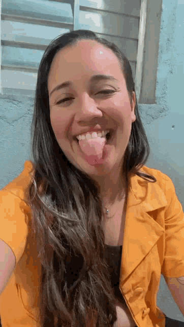 a woman in a yellow jacket sticks her tongue out