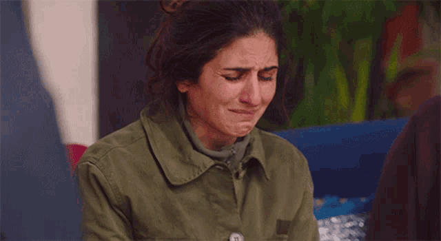 a woman in a green jacket is crying while sitting down