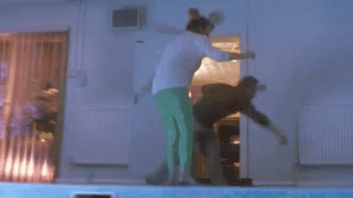 a man in a black shirt is standing next to a woman in a pool