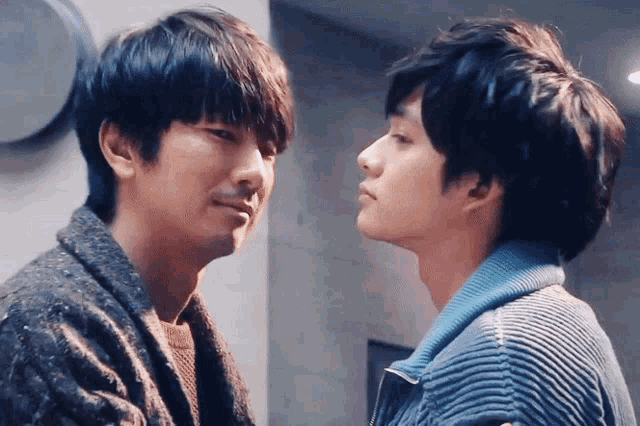 two men are looking at each other with one wearing a blue jacket