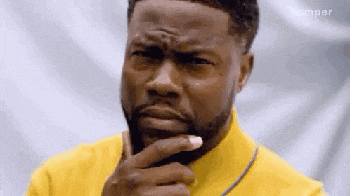 a man with a beard is holding his hand to his chin and looking at the camera .