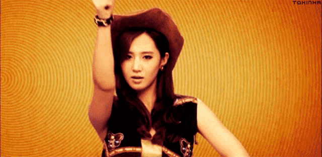 a woman wearing a cowboy hat is dancing with her hand in the air ..