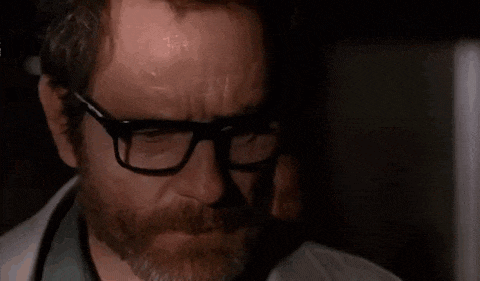 a man with a beard is looking at another man 's face .