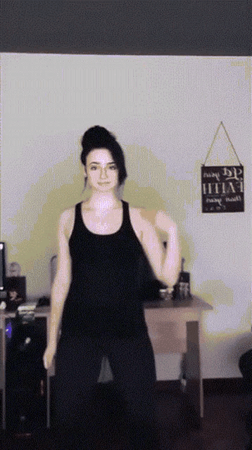a woman in a black tank top stands in front of a sign that says faith