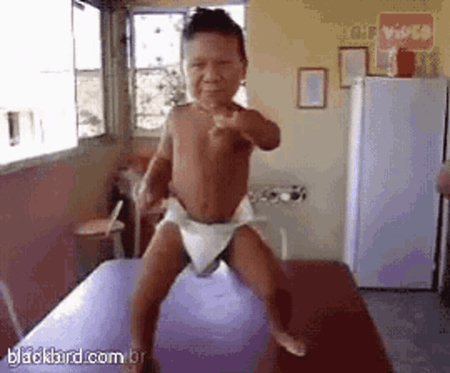 a baby in a diaper is dancing on a purple table