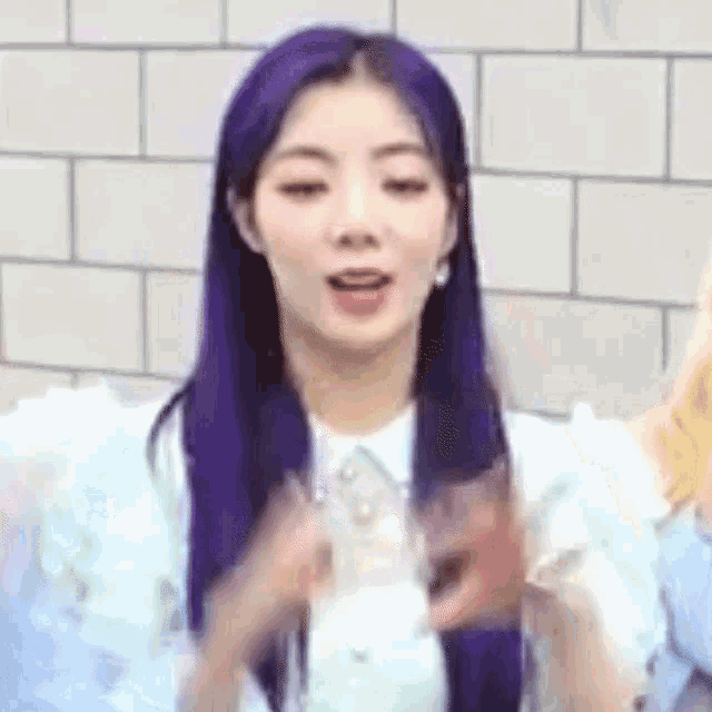 a woman with purple hair is holding a glass in her hand .